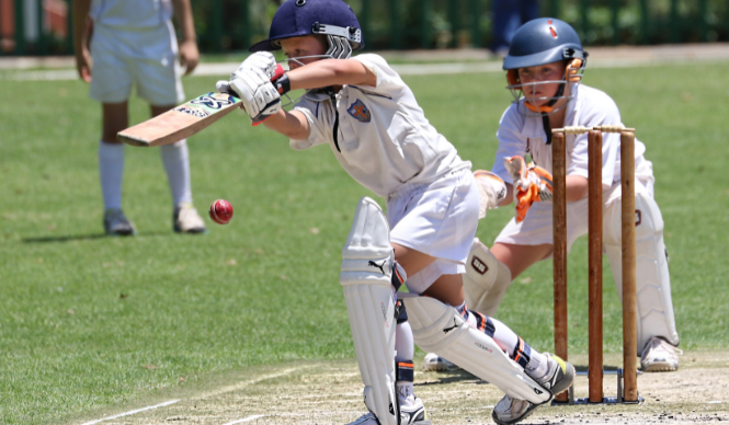 A cricket batsman playing a shot with a wicketkeeper behind the stumps.
